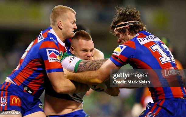 Blake Austin of the Raiders is tackled by Mitchell Barnett and Lachlan Fitzgibbon of the Knights during the round 25 NRL match between the Canberra...