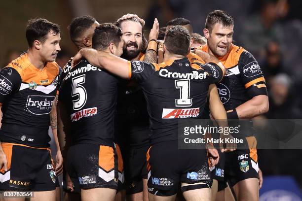 Aaron Woods of the Tigers celebrates with his team after scoring a try during the round 25 NRL match between the Wests Tigers and the North...