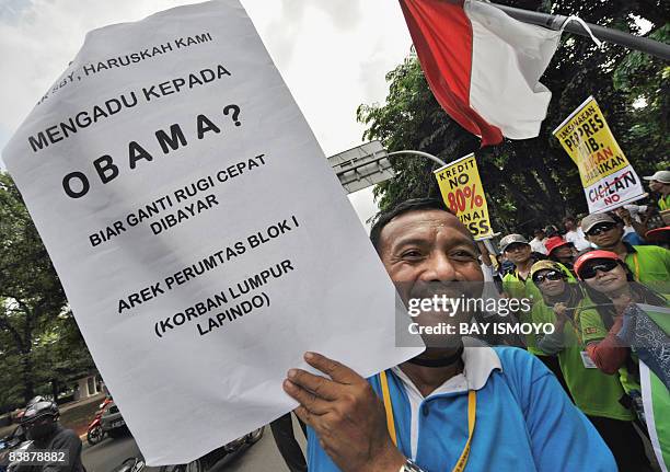 Victim of Indonesia's Lapindo mud volcano displays a placard reading "Mr. SBY do we have to bring our complain about to Obama" during a protest in...