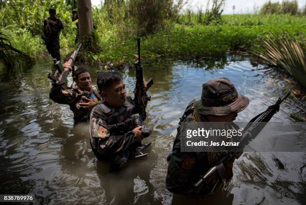 Moro Islamic Liberation Front Fighters and local police walk through a marshland on their way to the frontline of battle against extremists on August...