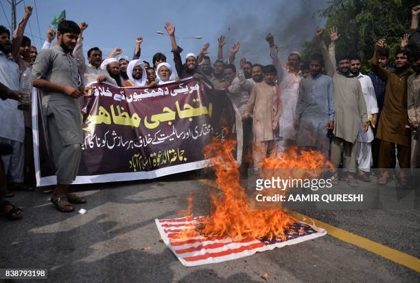Supporters of the Defence of Pakistan Council, a coalition of around 40 religious and political parties, shout slogans as they burn a US flag in...