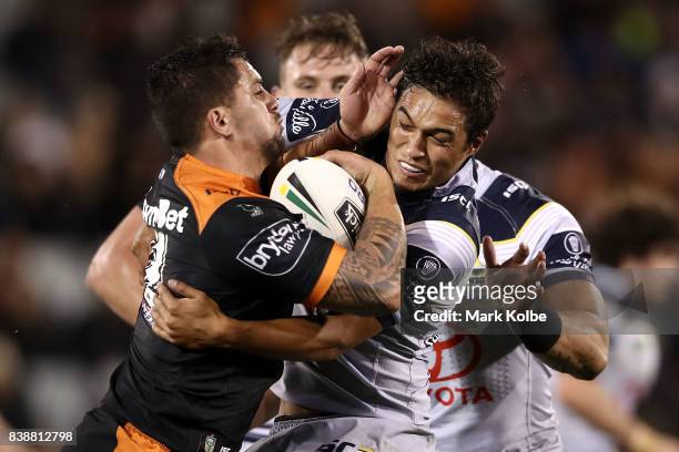 Josh Aloiai of the Tigers is tackled by Te Maire Martin of the Cowboys during the round 25 NRL match between the Wests Tigers and the North...