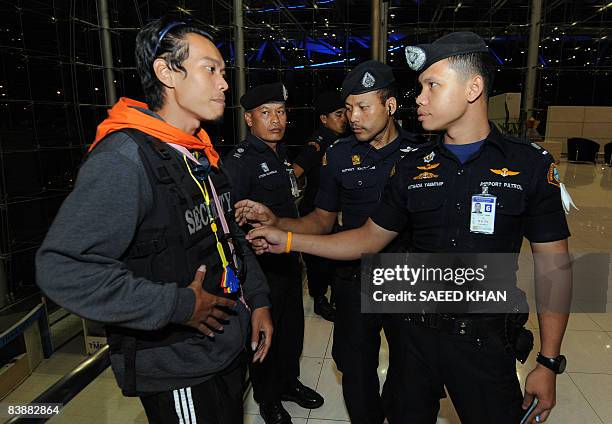 Airport Security force officers enquire about a bullet proof vest worn by an anti-government protestor while taking charge at the Suvarnabhumi...