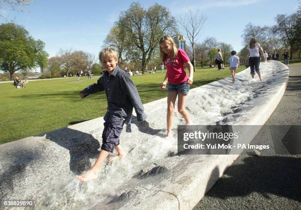 Thomas Matthews, aged 8, and his sister Anna, aged 10, with their mother Amanda playing in the water of the Princess Diana Memorial Fountain in Hyde...