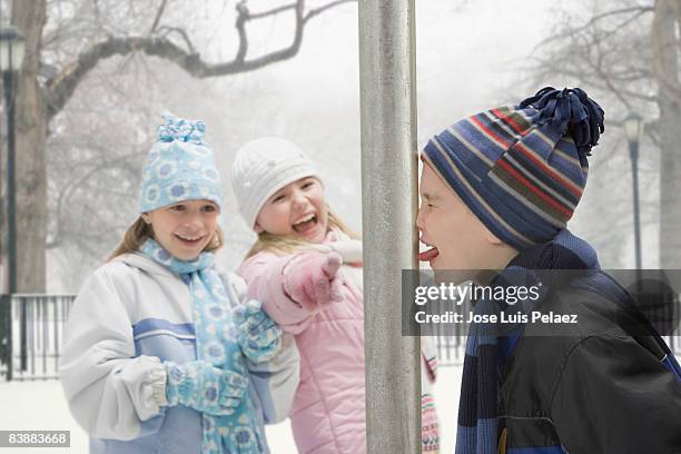two girls laughing at boy with tongue stuck - wedged stock pictures, royalty-free photos & images