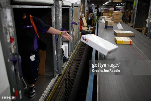 FedEx workers unload packages from shipping containers as they are sorted and placed on trucks to be delivered December 2, 2008 in Miami, Florida. As...