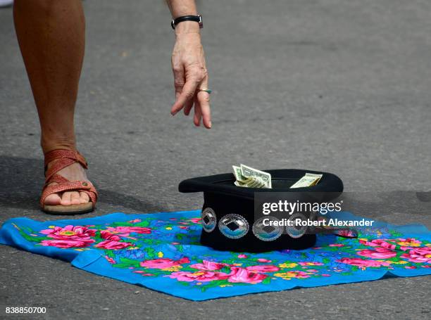 Woman places money in a hat during a performance by the Native America Edaakie Junior Dance Group from Zuni Pueblo near Gallup, New Mexico, at the...