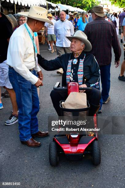 Former U.S. Senator Ben Nighthorse Campbell pauses to talk with Navajo artist Rick Nez at the Santa Fe Indian Market in Santa Fe, New Mexico. The...