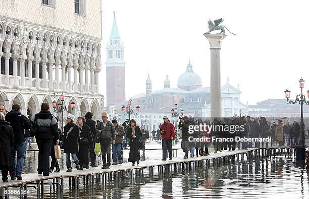 Tourists walk across on boards used to create walkways over the high water in the flooded Piazza San Marco on December 2, 2008 in Venice, Italy....