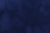 Background of dark blue suede fabric closeup. Velvet matt texture of navy blue nubuck textile