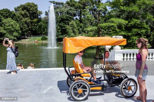 Family riding a rental quadricycle in Buen Retiro Park.