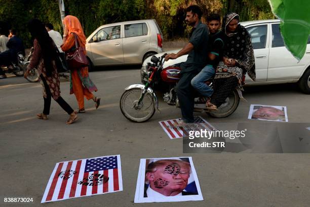 Pakistani motorcyclist rides over images of US President Donald Trump and a US flag on a street in Lahore on August 25, 2017. - Angry and offended...