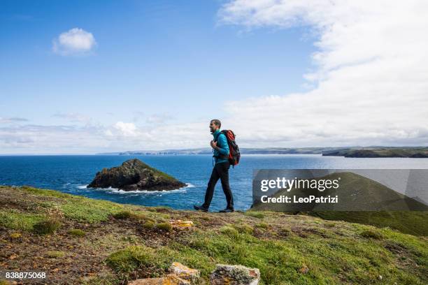 homme solitaire et voyageur explorant la côte rocheuse à cornwall, royaume-uni - littoral rocheux photos et images de collection