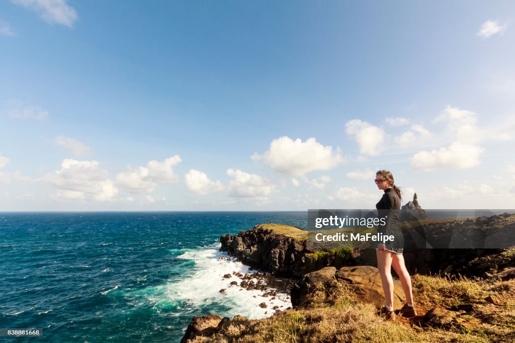 Mulher em pé de um penhasco em Fernando de Noronha