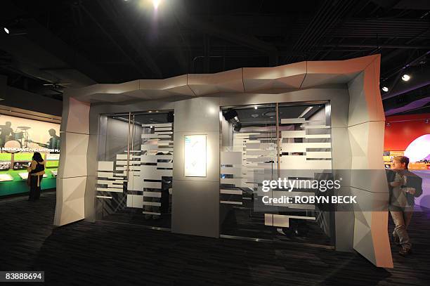 Visitor walks past two of eight self contained interactive pods in which visitors can participate in the process of creating music while guided by...