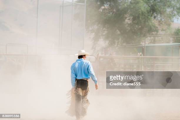 bull rider loopt door het stof na zijn rit - bull riding stockfoto's en -beelden