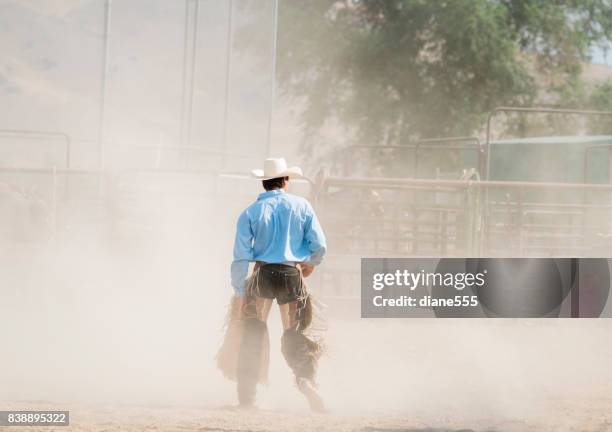 bull rider walks through the dust after his ride - calça de couro de cowboy imagens e fotografias de stock