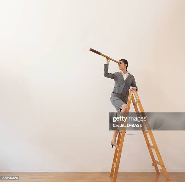 business woman on ladder with telescope - catalejo fotografías e imágenes de stock