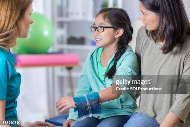 emergency room doctor talks with young injured patient - urgent care stock pictures, royalty-free photos & images