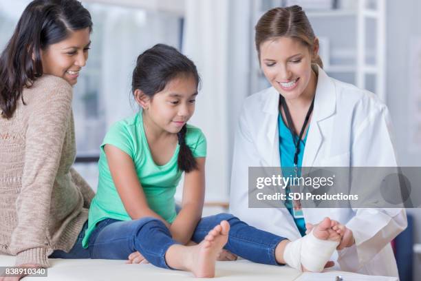 female doctor wraps young girl's injured ankle - sprain stock pictures, royalty-free photos & images