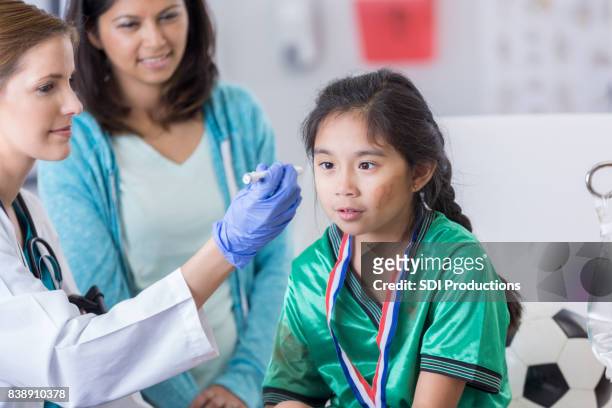 emergency room doctor examines young dazed soccer player - concussion stock pictures, royalty-free photos & images