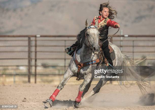 at a rodeo, very young cowgirl on her horse aiming at completing a cloverleaf pattern during the barrel racing event, also called gymkhana. - barrel race stock pictures, royalty-free photos & images