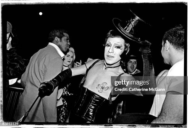 American drag performance artist Joey Arias, wearing a leather corset and elbow length black gloves, tips his top hat for a photo in December 1995 in...