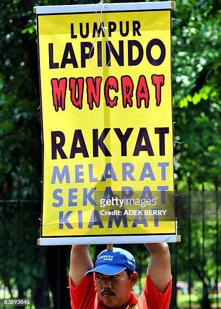 Victim of the Lapindo volcano eruption holds a banner reading "People Destitute, Dying, Afterlife" during a demonstration in front of the Indonesian...