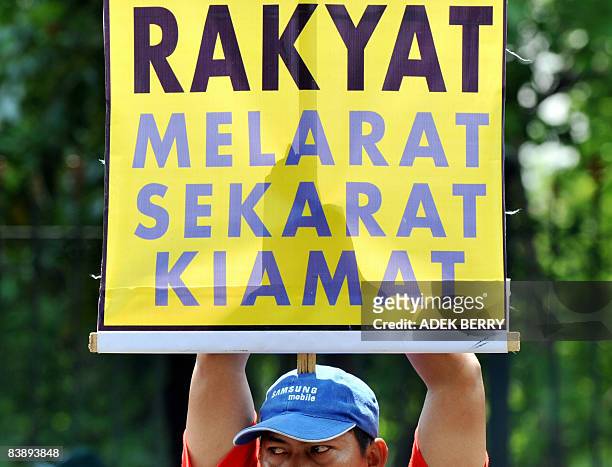 Victim of the Lapindo volcano eruption holds a banner reading "People Destitute, Dying, Afterlife" during a demonstration in front of the Indonesian...