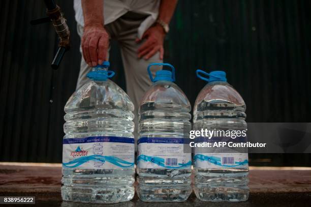 Man puts a tap on a plastic bottle after the distribution of water from a water tanker during a strong drought in Fuente de Piedra on August 25,...