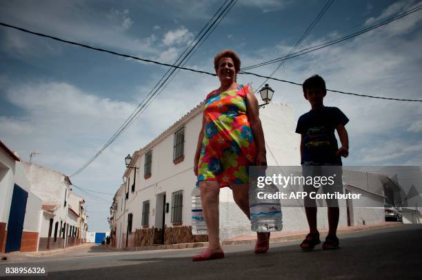 Woman carries plastic bottles after the distribution of water from a water tanker during a strong drought in Fuente de Piedra on August 25, 2017. /...