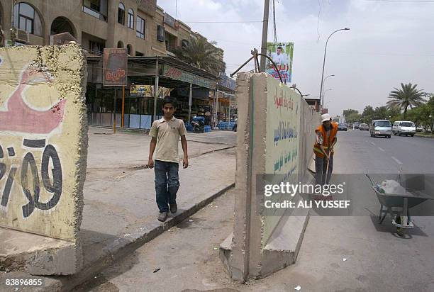 An Iraqi boy emerges from behind cement blast walls painted with advertisements denoting the shops behind in the Iraqi capital Baghdad on May 8,...