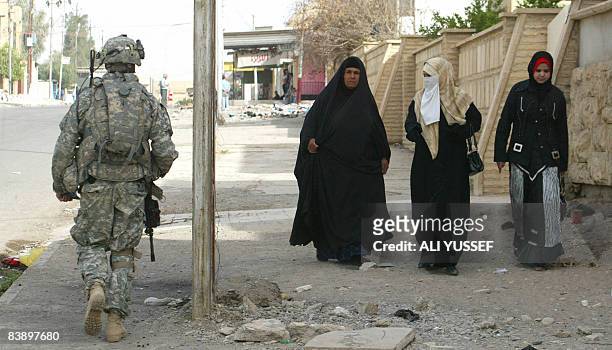 An US soldier from 3rd squadron 3rd armored cavalry walks past three Iraqi women while on a joint patrol with Iraqi soldiers of the 2nd division in...