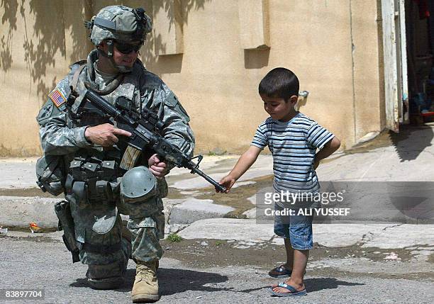 Soldier from 3rd squadron 3rd armored cavalry chats with a little Iraqi boy during a joint patrol with Iraqi soldiers of the 2nd division in the...