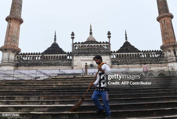 Man sweeps the stairs next to the mosque at the Bara Imambara, a colossal imambara complex in Lucknow, northern India, on August 25, 2017. / AFP...