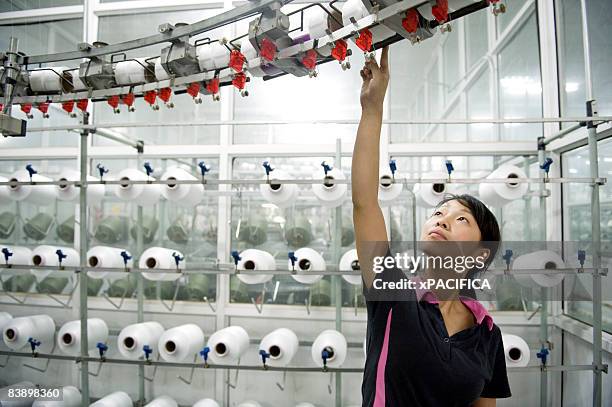 a employee tending to a knitting machine. - textile industry stock-fotos und bilder