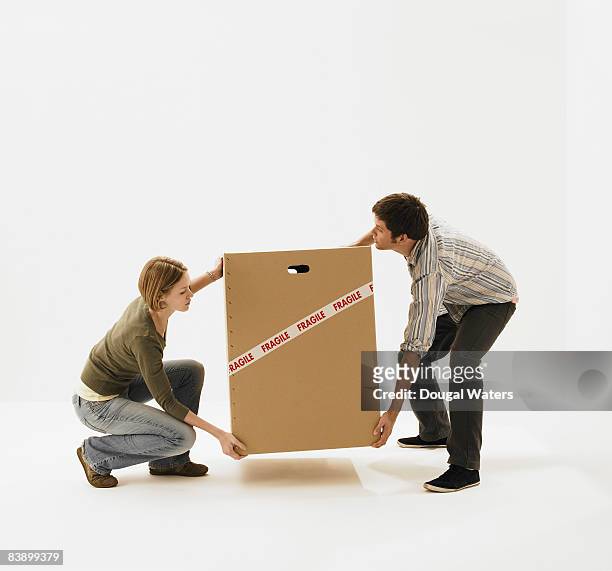 young couple carrying carboard box. - かがむ 人 横 ストックフォトと画像