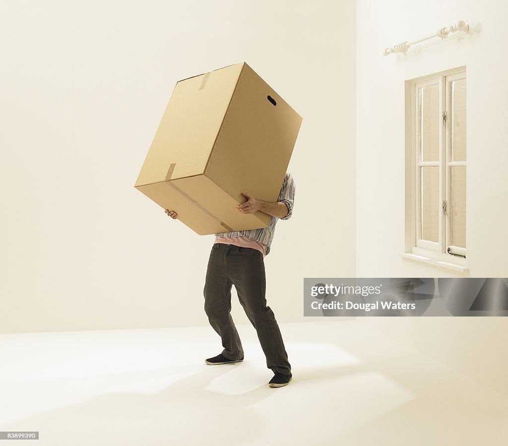 Young man holding heavy box.