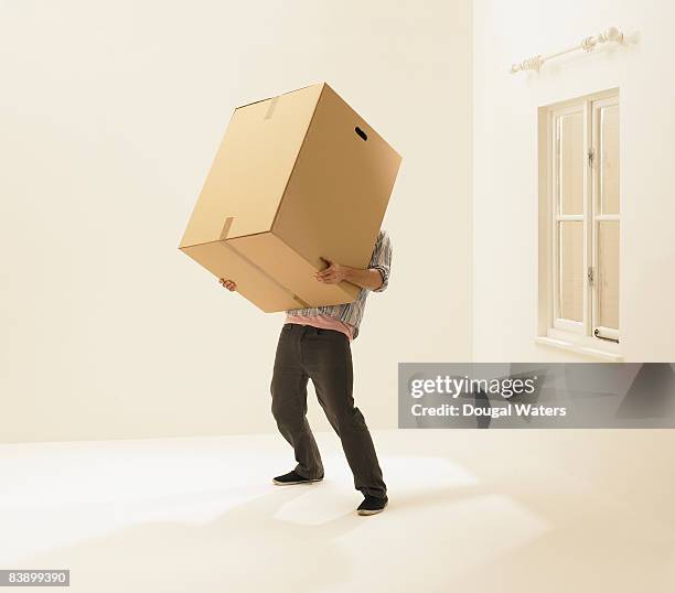 young man holding heavy box. - carrying bildbanksfoton och bilder