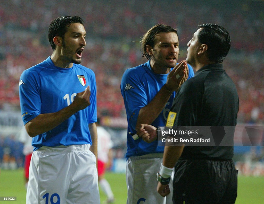 Gianluca Zambrotta (left) and Cristiano Zanetti (right) of Italy protest to referee Byron Moreno of Ecuador after he awarded a penalty to South Korea