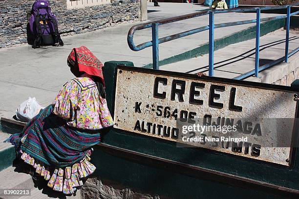 Woman sits beside a town sign in the farming and logging town of Creel on November 25, 2008 in Mexico. Creel is one of the main tourist attractions...