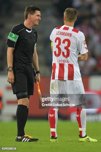 Linesman Stefan Lupp jokes with Matthias Lehmann of Koeln while they wait for the 4th official to come on as new referee during the Bundesliga match...