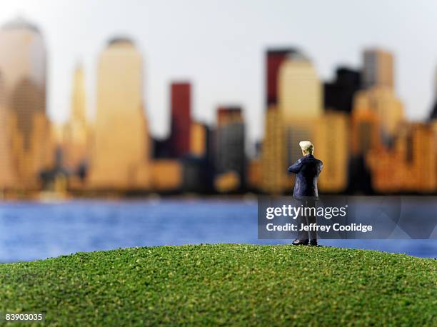 toy businessman looking at city - ciudades pequeñas fotografías e imágenes de stock