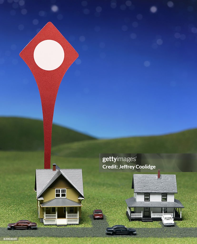Giant map pin locating toy house