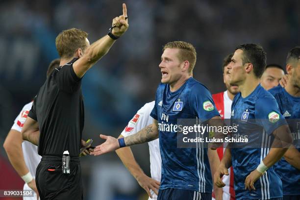 New referee Soeren Storks argues with Andre Hahn of Hamburg and Filip Kostic of Hamburg the Bundesliga match between 1. FC Koeln and Hamburger SV at...