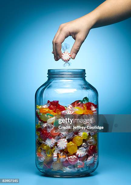 woman taking candy from jar - candy jar stock pictures, royalty-free photos & images