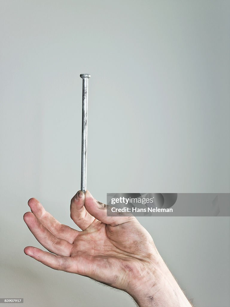 Hand holding one single nail