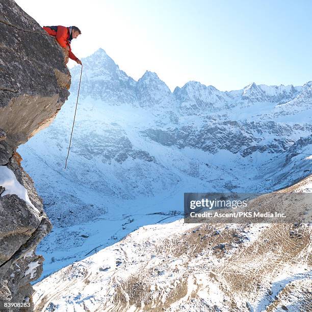 mountaineer dangles rope from overhanging cliff - leading edge stock pictures, royalty-free photos & images