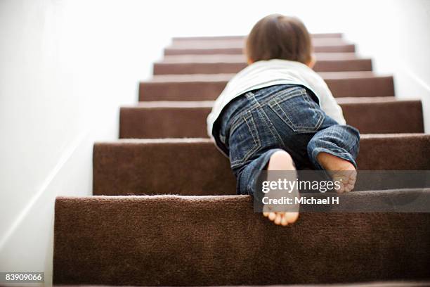 baby mounts the stairs by crawling - gatear fotografías e imágenes de stock