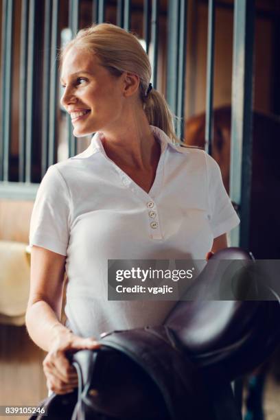 woman in a barn preparing for training - riding boot stock pictures, royalty-free photos & images